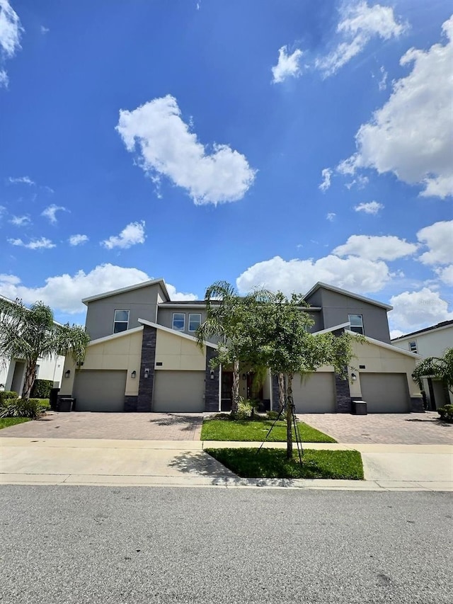 view of front of property with stone siding, stucco siding, an attached garage, and decorative driveway