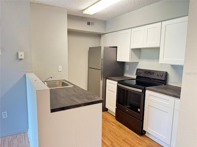 kitchen with a sink, stainless steel appliances, visible vents, light wood finished floors, and white cabinetry