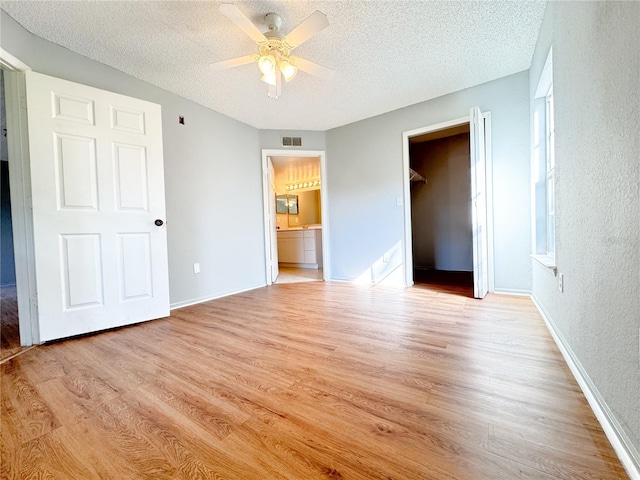 unfurnished bedroom featuring baseboards, light wood-style floors, visible vents, and a textured ceiling