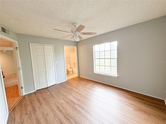 unfurnished bedroom with a closet, wood finished floors, a textured ceiling, visible vents, and a ceiling fan