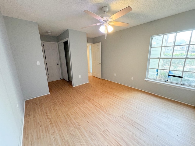 empty room featuring a ceiling fan, light wood-type flooring, and a textured ceiling