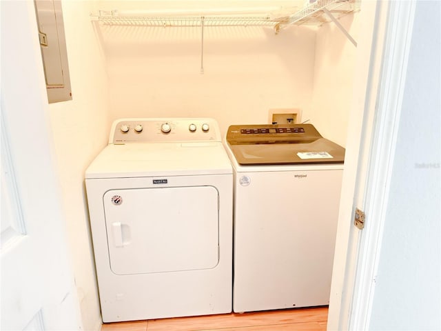 washroom with washing machine and clothes dryer, laundry area, light wood-type flooring, and electric panel