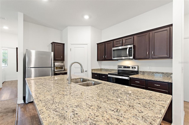 5816 Beefmaster Rd, Saint Cloud, FL 34771 - kitchen with appliances with stainless steel finishes, a sink, a kitchen island with sink, dark brown cabinetry, and wood finished floors
