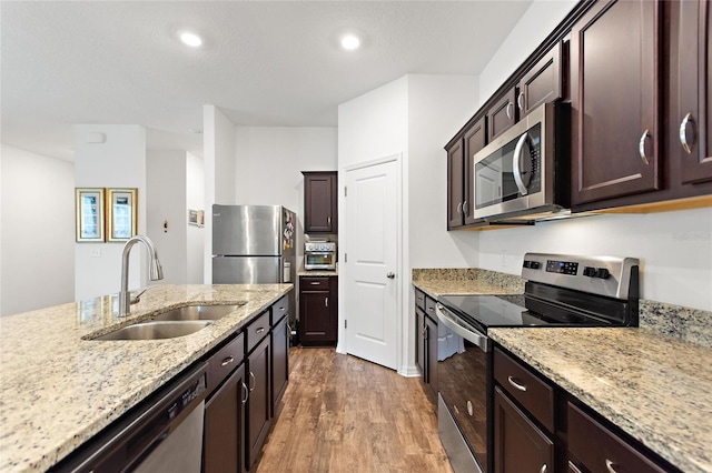 5816 Beefmaster Rd, Saint Cloud, FL 34771 - kitchen featuring appliances with stainless steel finishes, a sink, light wood-type flooring, dark brown cabinetry, and light stone countertops