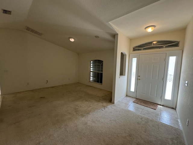 tiled entryway with vaulted ceiling, carpet floors, and visible vents