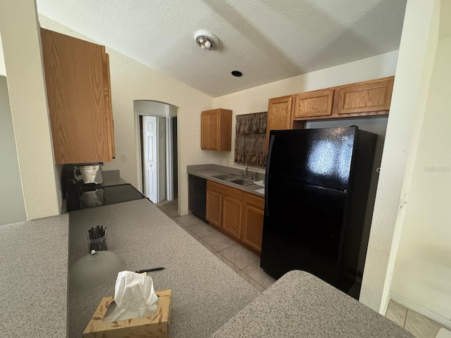 kitchen featuring light tile patterned floors, a sink, brown cabinets, black appliances, and light countertops