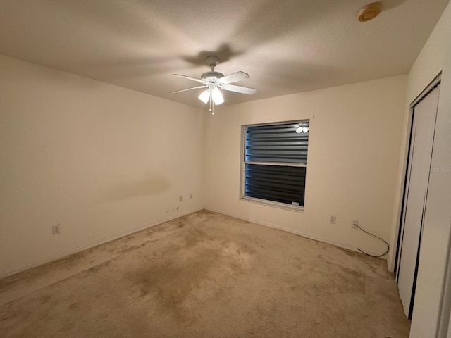unfurnished bedroom with light colored carpet, a closet, baseboards, and ceiling fan