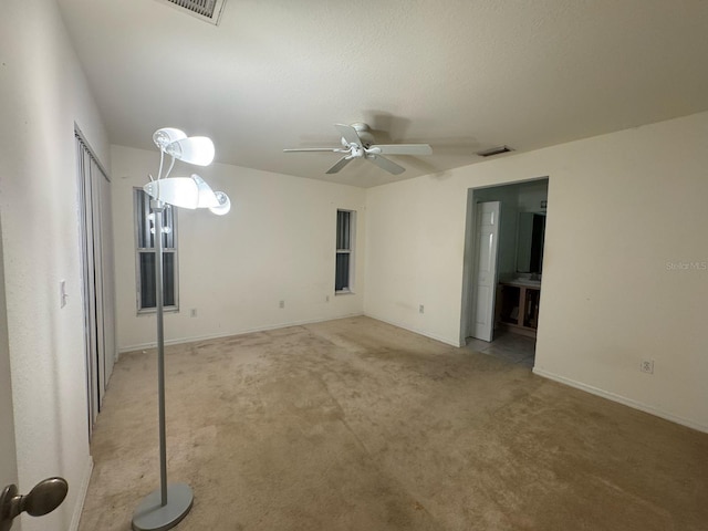 spare room with visible vents, baseboards, a ceiling fan, and light carpet