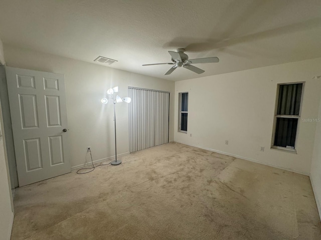 empty room with visible vents, baseboards, a ceiling fan, and carpet floors