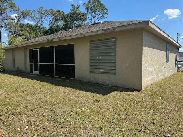 back of house with stucco siding and a lawn