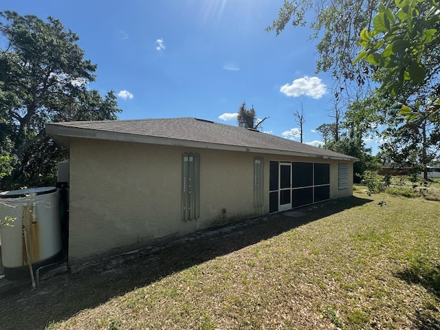 back of property featuring a lawn, stucco siding, and a sunroom