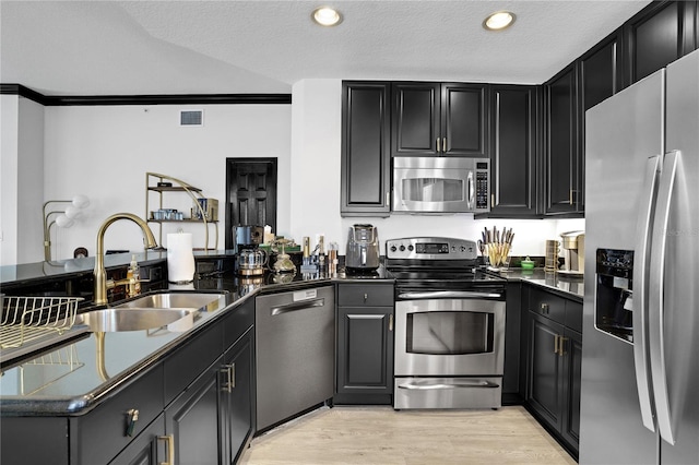 kitchen with appliances with stainless steel finishes, visible vents, a sink, and dark cabinets