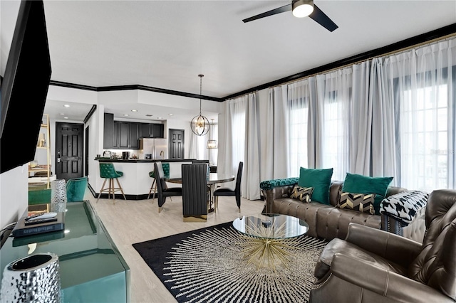 living area with a ceiling fan, light wood-style flooring, and crown molding