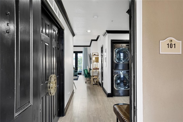interior space featuring laundry area, crown molding, stacked washer and clothes dryer, light wood finished floors, and baseboards