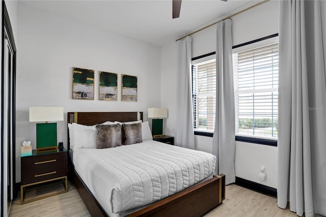 bedroom featuring baseboards, light wood-type flooring, and a ceiling fan