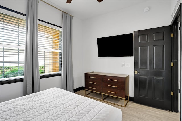 bedroom featuring light wood finished floors, baseboards, and ceiling fan