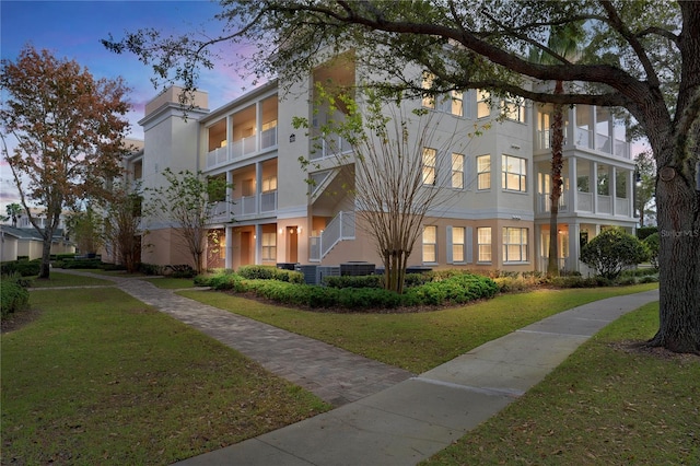 view of front of house featuring a yard, central air condition unit, and stucco siding