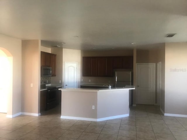 3102 Westbrook Rd, Kissimmee, FL 34746 - kitchen featuring stainless steel microwave, fridge, visible vents, black electric range, and arched walkways