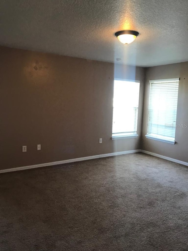 3102 Westbrook Rd, Kissimmee, FL 34746 - spare room featuring baseboards, dark carpet, and a textured ceiling
