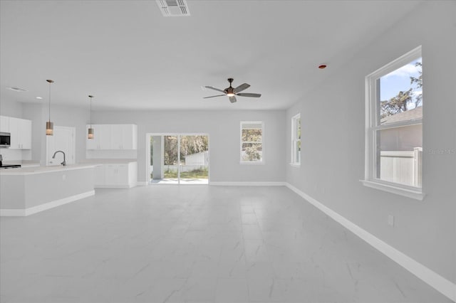 unfurnished living room with visible vents, baseboards, a ceiling fan, and a sink