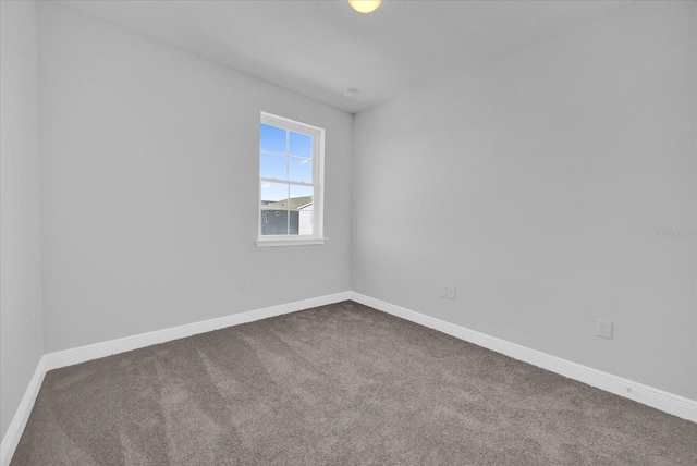 unfurnished room featuring dark colored carpet and baseboards