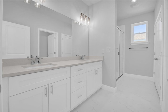 bathroom with double vanity, marble finish floor, a stall shower, and a sink
