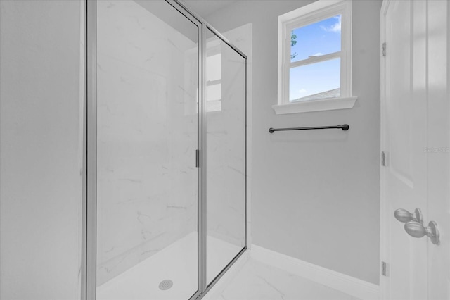 full bath with marble finish floor, a marble finish shower, and baseboards