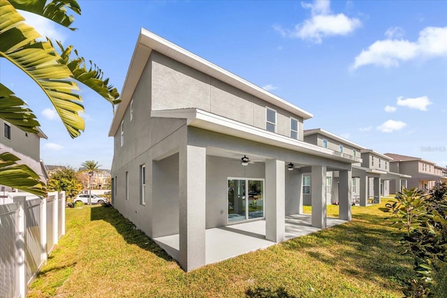 rear view of property featuring stucco siding, a lawn, ceiling fan, and a patio area