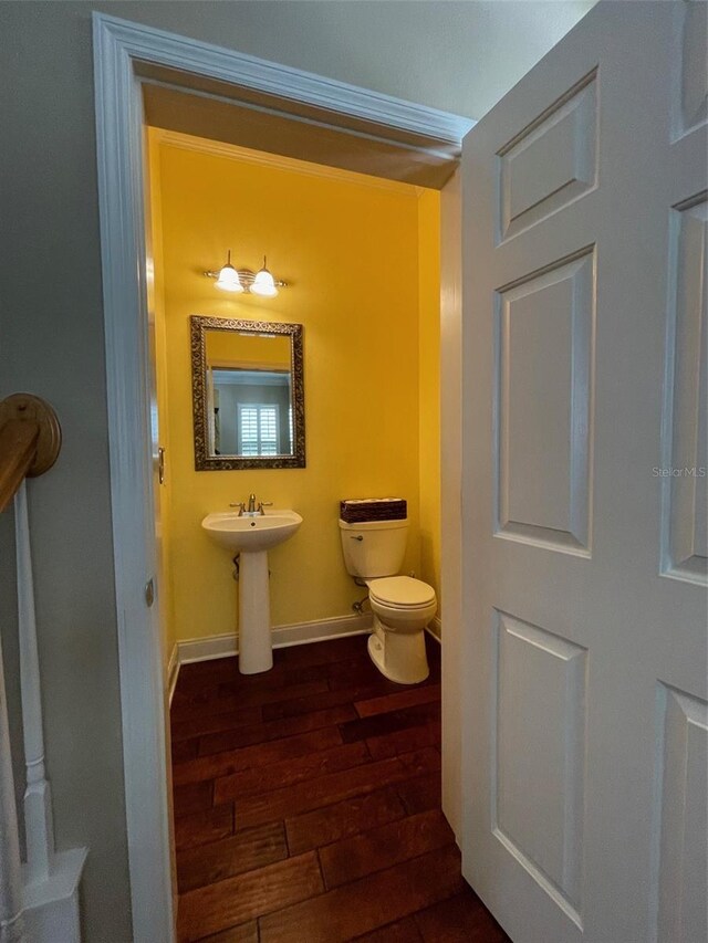 907 Pawstand Rd, Celebration, FL 34747 - half bathroom featuring wood finished floors, toilet, baseboards, and a sink