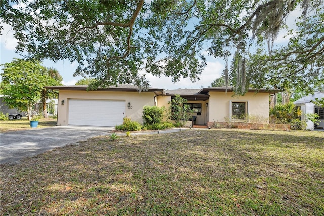 single story home featuring a front lawn, driveway, stucco siding, and a garage
