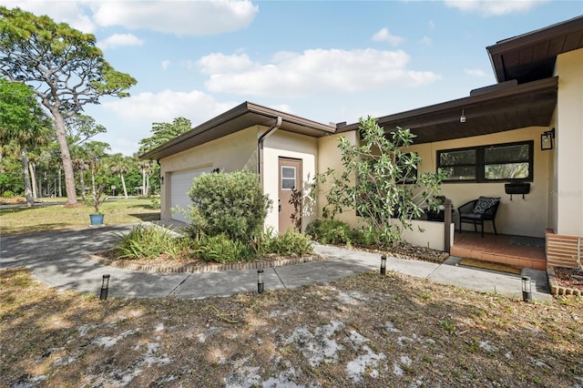exterior space with covered porch, stucco siding, and a garage