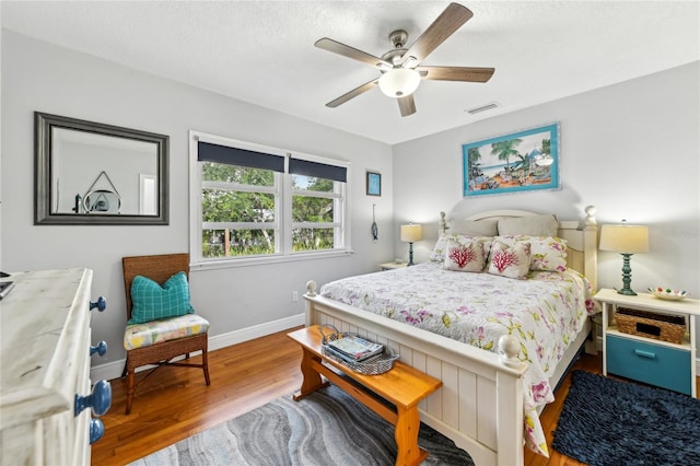 bedroom with wood finished floors, visible vents, baseboards, and ceiling fan
