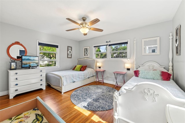 bedroom featuring baseboards, multiple windows, ceiling fan, and wood finished floors