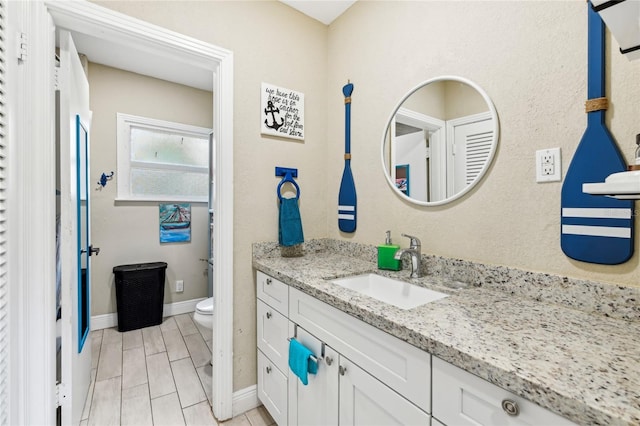bathroom featuring vanity, toilet, and baseboards