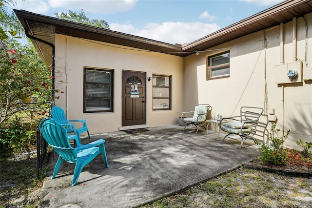entrance to property featuring a patio area and stucco siding