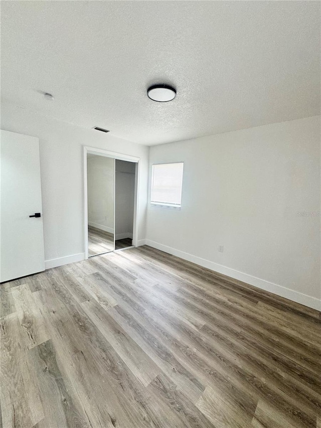 1098 Leeway Ct, Orlando, FL 32810 - unfurnished bedroom with a textured ceiling, a closet, baseboards, and wood finished floors
