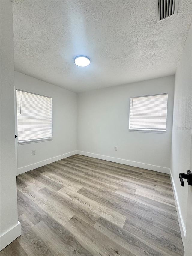 1098 Leeway Ct, Orlando, FL 32810 - empty room with a textured ceiling, visible vents, wood finished floors, and baseboards