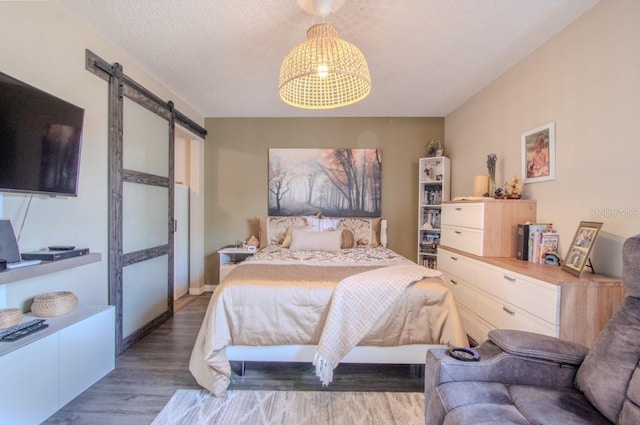 bedroom with a chandelier, a barn door, and wood finished floors