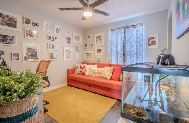 living area featuring a textured ceiling, baseboards, ceiling fan, and carpet floors