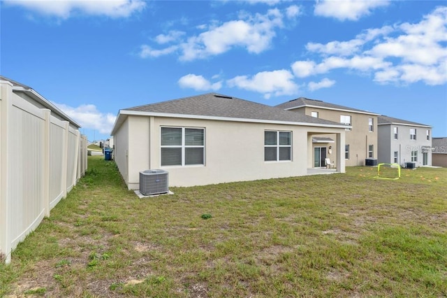 rear view of property featuring a yard, stucco siding, and central AC