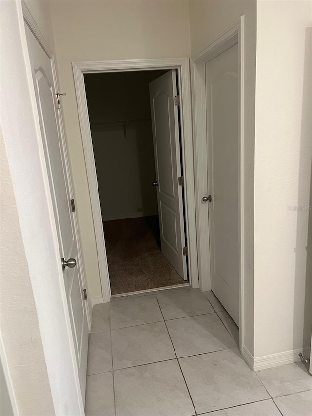 hallway featuring light tile patterned floors and baseboards