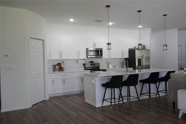 kitchen with a sink, dark wood finished floors, an island with sink, light countertops, and appliances with stainless steel finishes