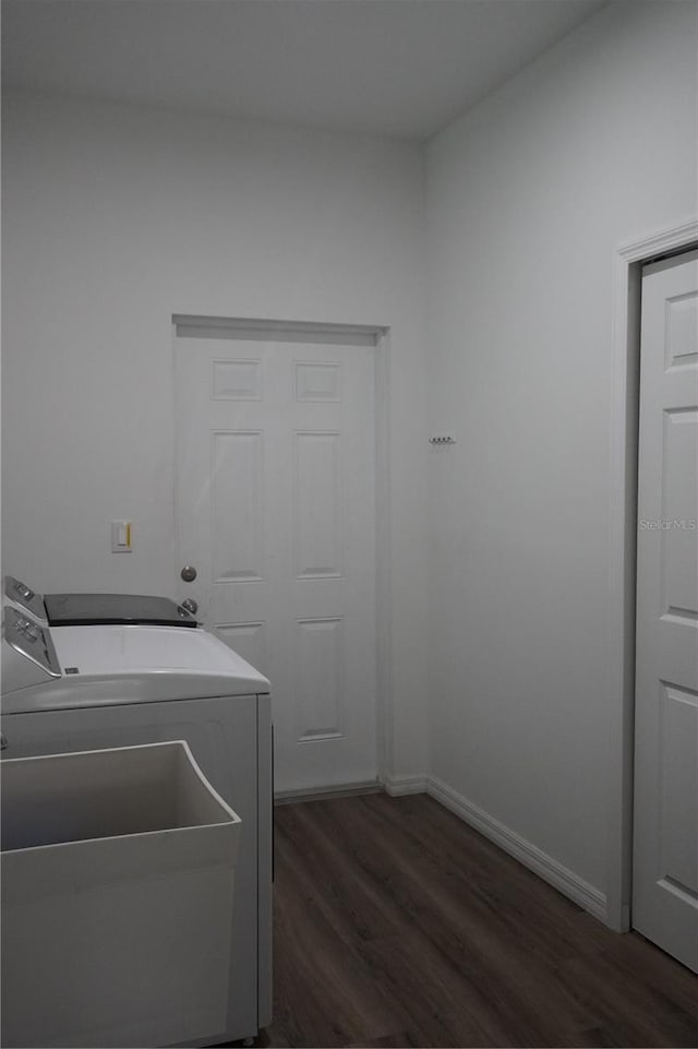 clothes washing area with laundry area, washer and clothes dryer, dark wood-style flooring, and baseboards