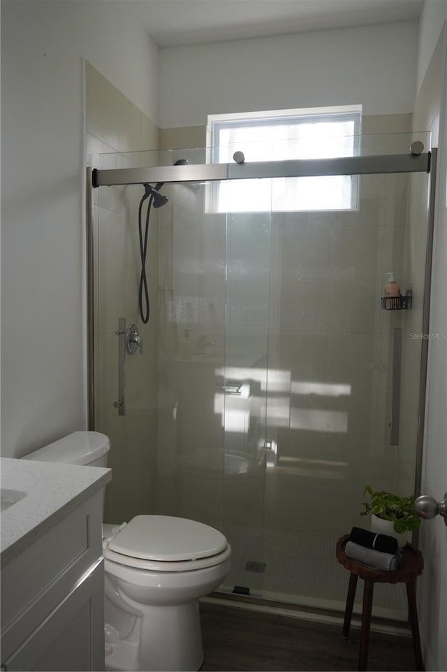 bathroom featuring vanity, toilet, a shower stall, and wood finished floors