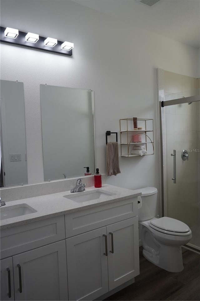 full bathroom featuring a stall shower, toilet, a sink, and wood finished floors