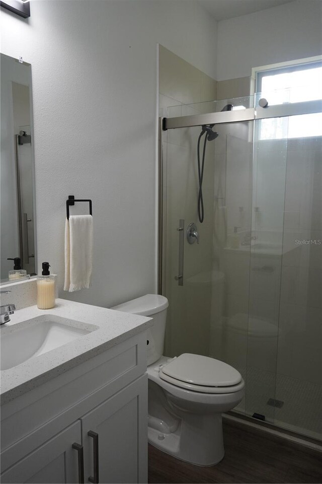 full bathroom featuring a stall shower, vanity, toilet, and wood finished floors