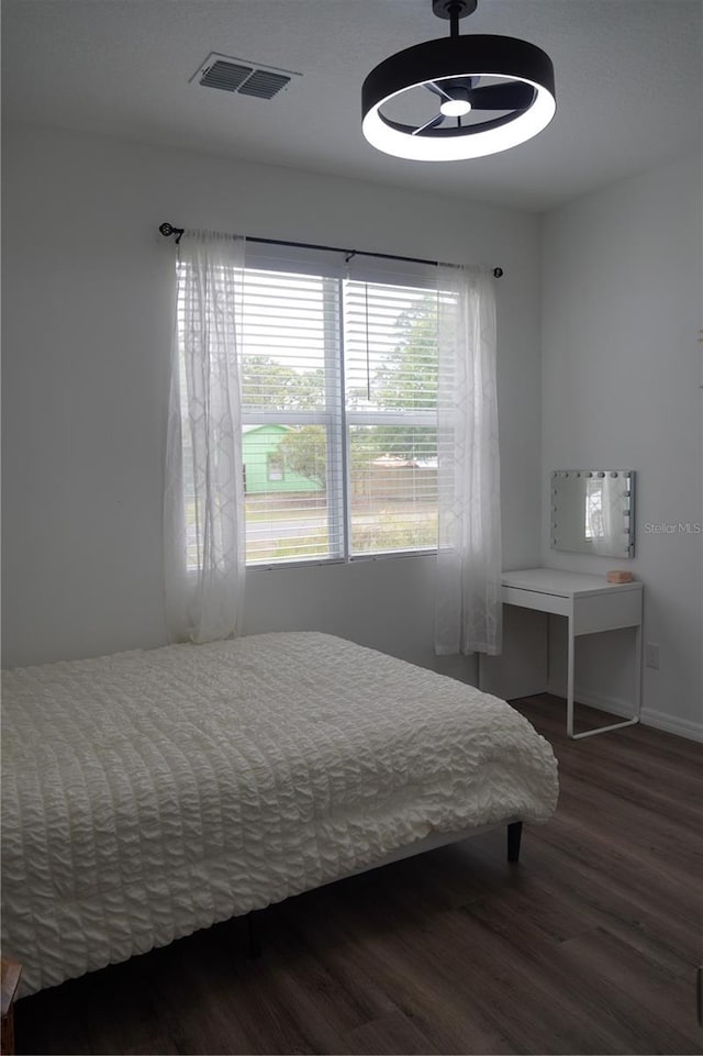 bedroom with baseboards, visible vents, and wood finished floors