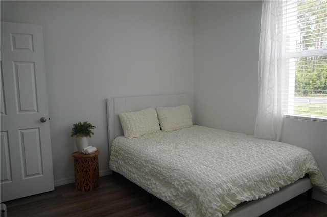 bedroom with baseboards and dark wood-type flooring