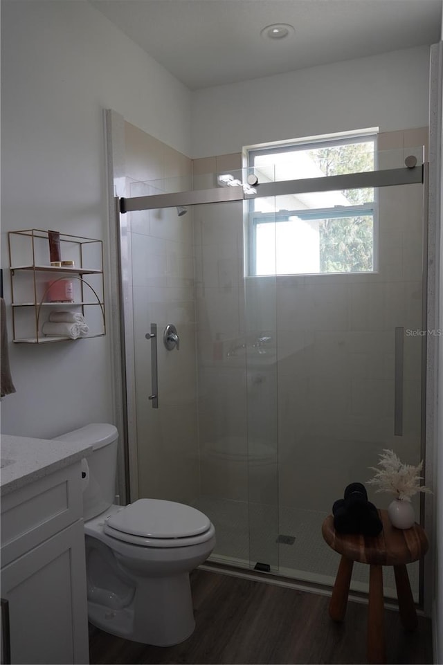bathroom with vanity, toilet, a shower stall, and wood finished floors