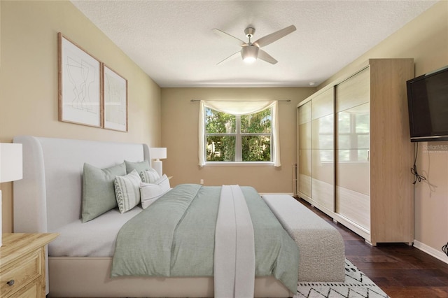 bedroom with dark wood-style flooring, a ceiling fan, a textured ceiling, and baseboards